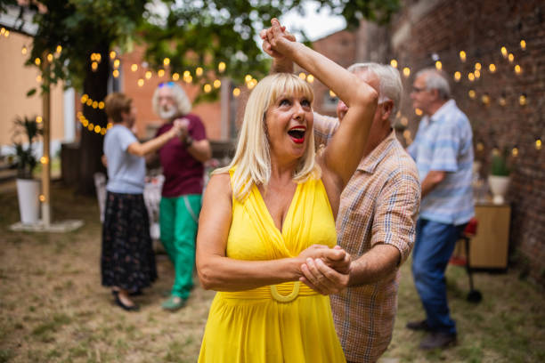 Senior couples spending fun time together dancing on party in backyard on summer day stock photo