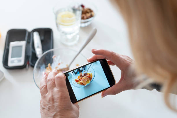 Senior diabetic woman photographing  a  her breakfast at home stock photo