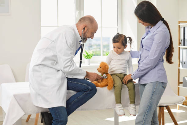 Senior doctor with a stethoscope listens to a little girl with mother patients in the hospital. stock photo