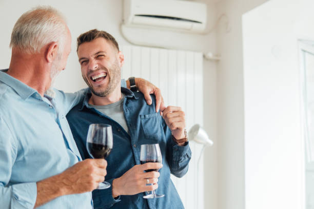 Senior father hugging adult son Male part of the family hugging and drinking alcohol fathers day stock pictures, royalty-free photos & images
