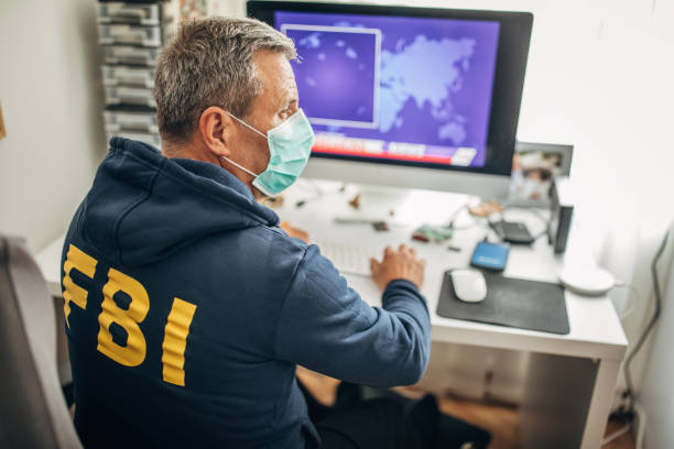 старший агент фбр в защитной маске работает в офисе - fbi стоковые фото и изображения