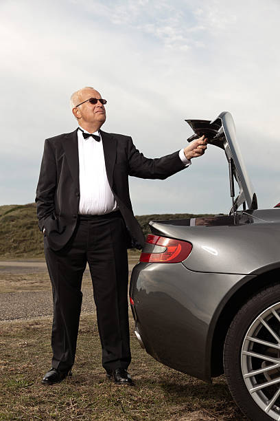 Senior good looking happy relaxed retired man with his sports car in...