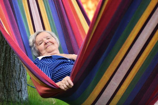 Senior happy woman resting on a hammock in garden. stock photo
