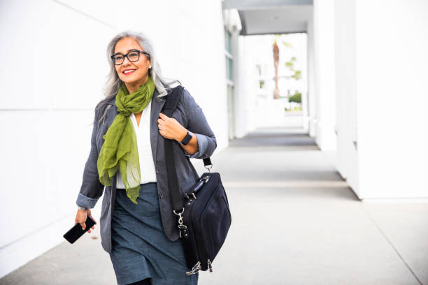 senior hispanic businesswoman walking down hallway - woman walk imagens e fotografias de stock