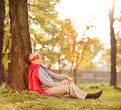 Senior in superhero outfit leaning on tree in park shot with tilt and shift lens