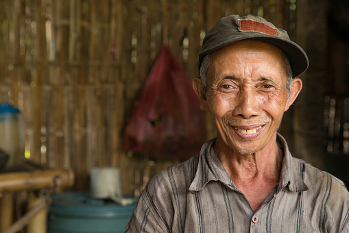 Senior Indonesian farmer smiling portrait in hut.