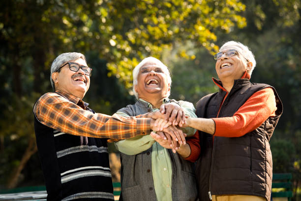 Senior male friends having fun at park Cheerful senior male friends stacking hands together at park LAUGH stock pictures, royalty-free photos & images