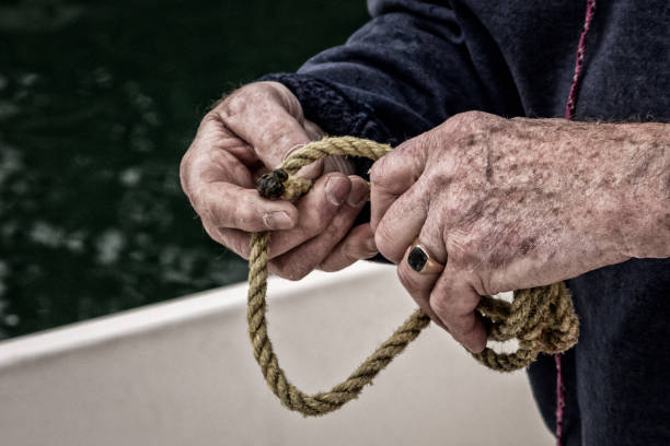 Senior Male Hands Tying Rope on a Boat Senior Male Hands Tying Rope on a Boat hands tied up stock pictures, royalty-free photos & images
