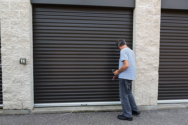 Senior male unlocking a storage warehouse senior male using his key to open a lock at his storage warehouse self storage stock pictures, royalty-free photos & images