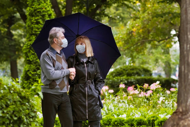 Senior man and woman in face mask. Virus outbreak Senior man and woman in face mask. Virus outbreak. Retired couple walking in a park under quarantine during coronavirus outbreak. Surgical masks to prevent sickness. People in hospital yard. russian mature women stock pictures, royalty-free photos & images