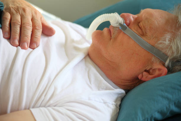 Senior man asleep wearing CPAP device stock photo