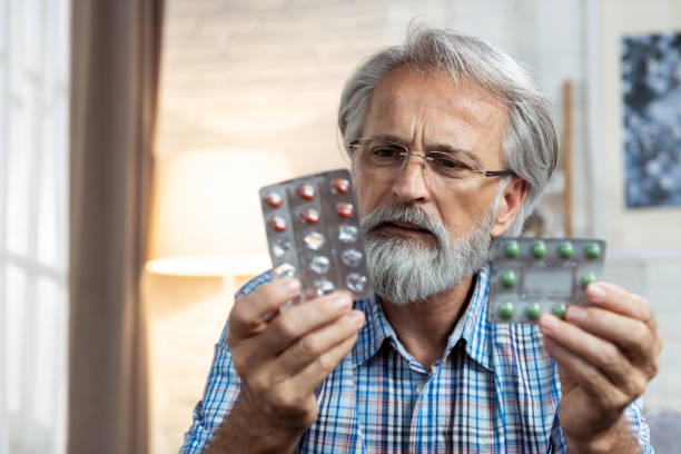 Senior man can't remember which pill to take stock photo