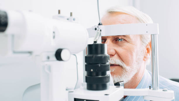 Senior man getting eye exam at clinic, close-up Senior patient checking vision with special eye equipment optometrist stock pictures, royalty-free photos & images