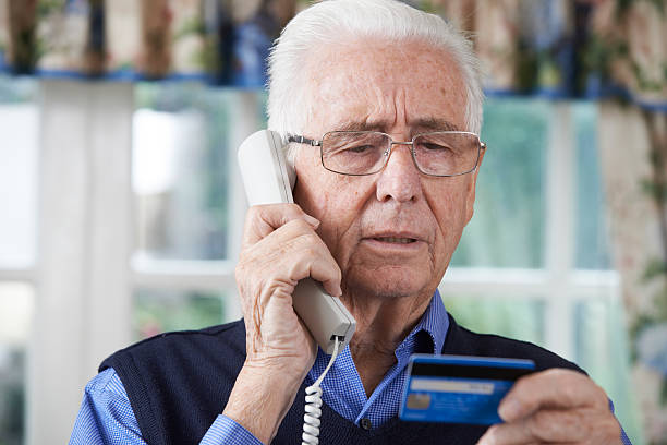 Senior Man Giving Credit Card Details On The Phone Senior Man Giving Credit Card Details On The Phone white collar crime stock pictures, royalty-free photos & images