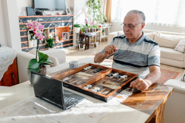 Senior man having great time , playing backgammon Senior man having great time , playing backgammon backgammon stock pictures, royalty-free photos & images