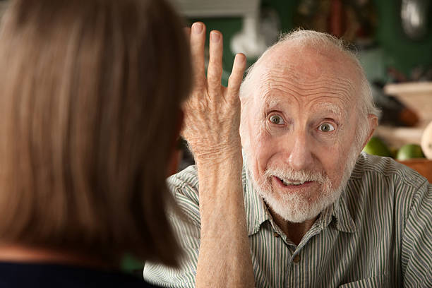 Senior man holding his arm up to woman facing him stock photo