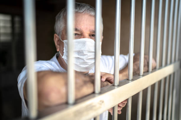 Senior man in isolation at home for virus outbreak looking through window Senior man in isolation at home for virus outbreak looking through window prison stock pictures, royalty-free photos & images