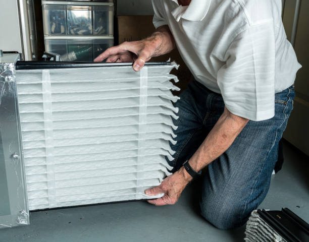 Senior man inserting a new air filter in a HVAC Furnace Senior caucasian man checking a clean folded air filter in the HVAC furnace system in basement of home replacement stock pictures, royalty-free photos & images