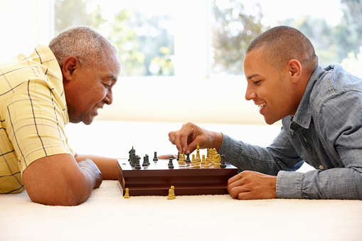 Senior man playing chess with son