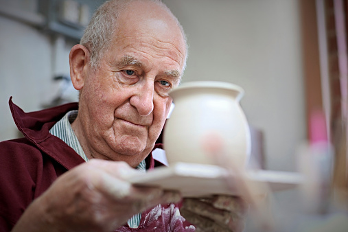 Senior man potter inspecting a clay jar