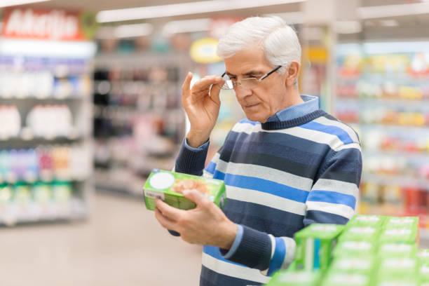 Senior man reading food label at a grocery store stock photo