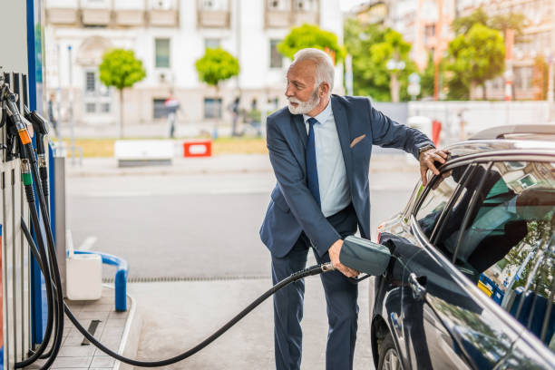 Senior man refueling his car the gas station. stock photo
