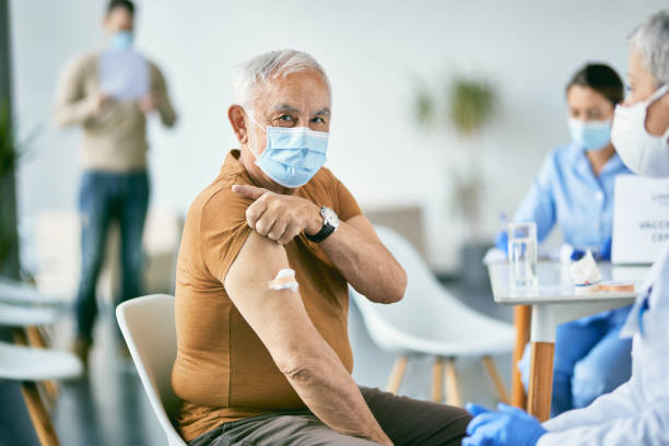 Senior man showing his arm after receiving vaccine against COVI-19 at vaccination center. stock photo
