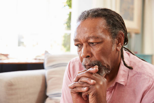 Senior Man Sitting On Sofa At Home Suffering From Depression Senior Man Sitting On Sofa At Home Suffering From Depression sad old black man stock pictures, royalty-free photos & images