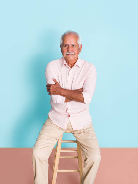 Senior man sitting with arms crossed and looking at camera stock photo