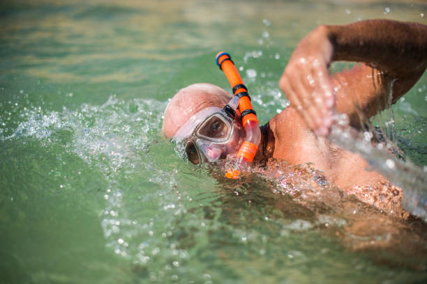 Senior man swimming in ocean stock photo