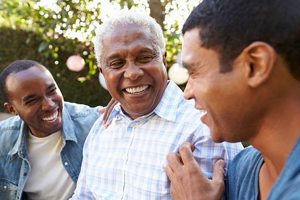 senior man talking with his adult sons in garden, - far och son bildbanksfoton och bilder