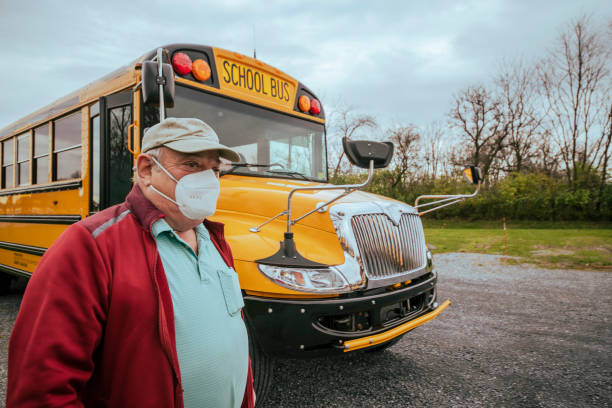 Senior man, the bus driver, in front of a school bus. School bus driver at work school bus driver stock pictures, royalty-free photos & images