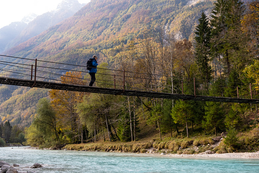 Senior Man walking on the Suspension bridge over Soča River in Julian Alps, Trenta, Bovec, Slovenia, Europe.