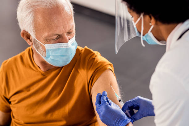 starszy mężczyzna noszący maskę na twarz podczas przyjmowania szczepionki w klinice medycznej. - covid vaccine zdjęcia i obrazy z banku zdjęć