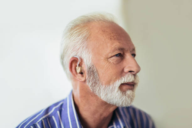 старший человек, нося слуховой аппарат - hearing aids стоковые фото и изображения