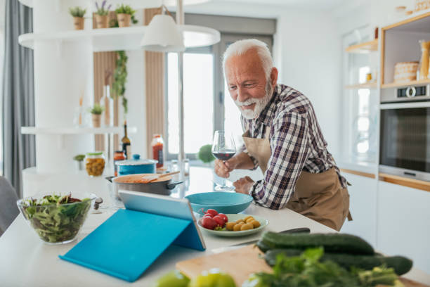 Senior man with gray hair at home Senior man with gray hair at home cooking at home cooking class stock pictures, royalty-free photos & images