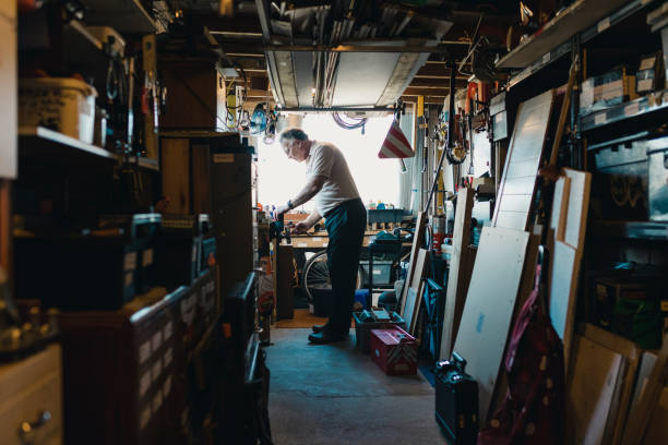 Senior Man Working in his Workshop Senior man is working in his shed on a woodwork project. He is fatsening something in to a vice. small business saturday stock pictures, royalty-free photos & images