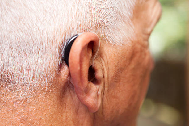 Senior Man's Ear with Hearing Aid A senior man's ear with with a very modern, low-profile and discrete hearing aid. This is a behind-the-ear, open-ear style of hearing aid and represents the latest in hearing aid technology. Focus is on the area where the tube enters the ear, the back of the ear and over-ear portion of the hearing aid are slightly soft at 100%. hearing aids stock pictures, royalty-free photos & images