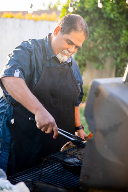 senior mexikanische mann grillen steaks am grill - fett verbrennen senior stock-fotos und bilder
