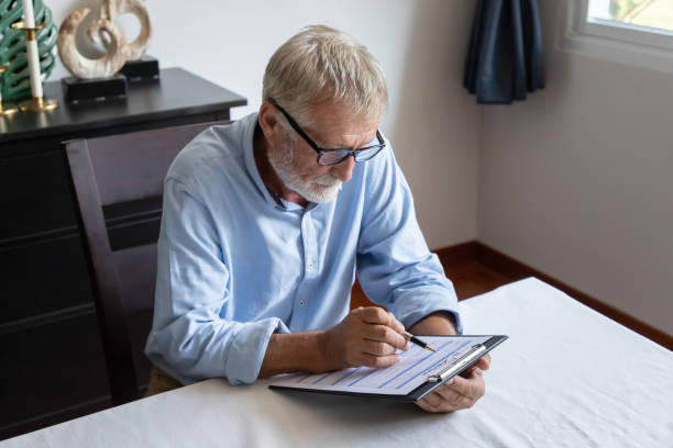 Senior old man elderly reading and examining reverse mortgage application form stock photo