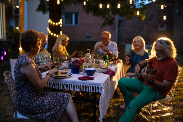 Senior people enjoying music and good companionship during garden party at night stock photo