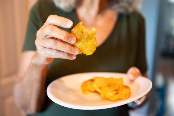 Senior Puerto Rican Woman's Hands Eating Tostones in Orlando Florida This is a close up of a senior Puerto Rican woman's hands as she eats tostones made from fried green plantains in Orlando, Florida. puerto rican women stock pictures, royalty-free photos & images