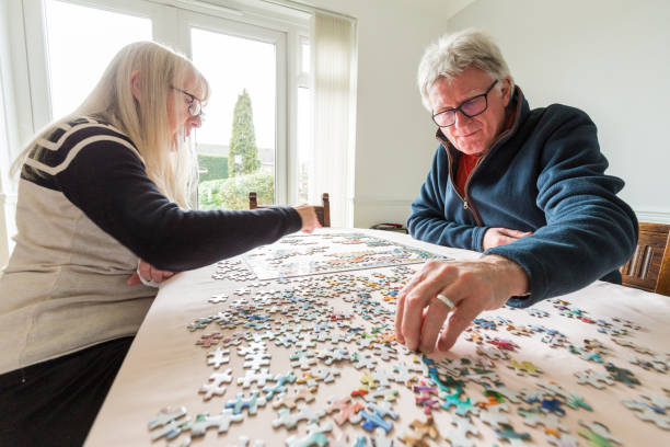 Senior retired couple doing jigsaw puzzle together at home stock photo