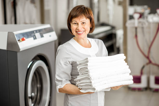 Senior washwoman in the laundry Portrait of a senior washwoman in uniform standing with towels in the hotel laundry laundromat photos stock pictures, royalty-free photos & images