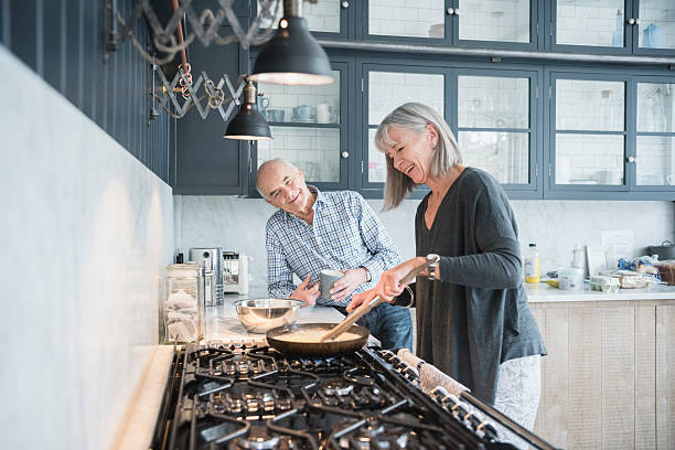 senior frau kochen abendessen im gespräch mit ihrem ehemann vor - oma kocht stock-fotos und bilder