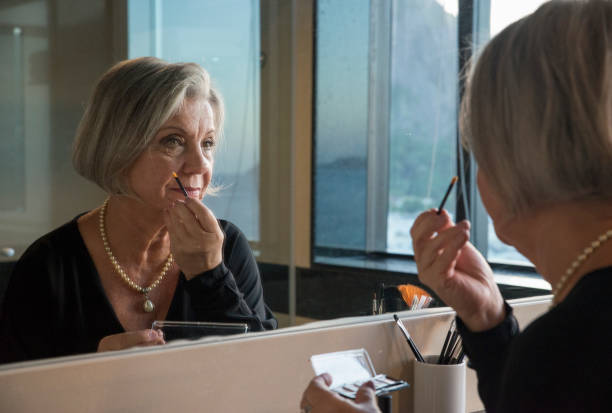 Senior Woman Doing Makeup In Front Of Mirror stock photo