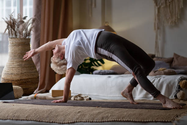 Senior woman doing standing mermaid stretch training at home.  sexy old  woman exercising stock pictures, royalty-free photos & images