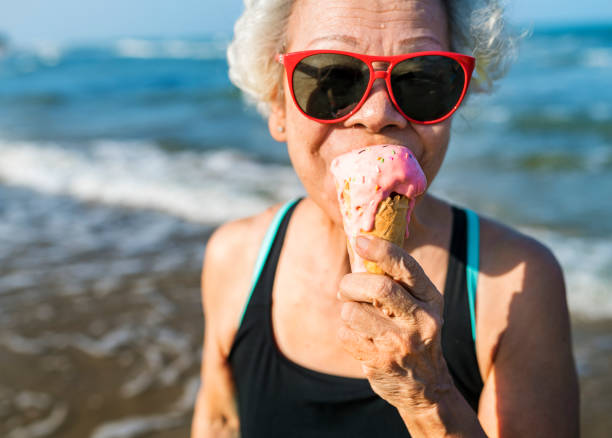 Senior woman eating an ice-cream Senior woman eating an ice-cream fun stock pictures, royalty-free photos & images