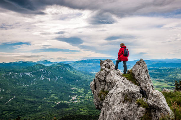 Senior Woman Enjoying the amazing landscape High in the Mountains Senior woman in the mountains looking at the view, Slovenia, Europe. All logos removed. NIKON D3X, 24.0-70.0 mm f/2.8. mountain peak stock pictures, royalty-free photos & images