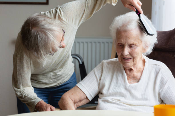 Senior woman getting her hair done by caregiver stock photo